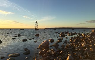 Rocky coastline at dusk with calm sea and orange horizon in Estonia