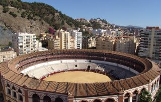 Aerial view of traditional Spanish bullring in mountainous urban surroundings – circular arena with tiered seating