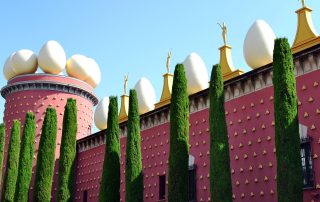 Exterior of the Dalí Theatre-Museum in Figueres – red facade with golden sculptures and egg-shaped rooftop ornament