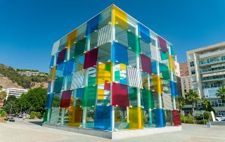 Colorful glass cube of Centre Pompidou Málaga – contemporary art museum facade in bright sunlight