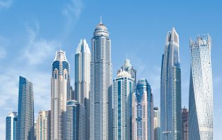 Cluster of sleek modern towers in Dubai skyline against blue sky