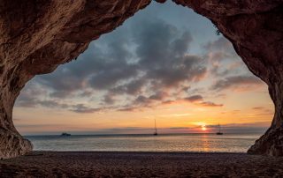 Sunset framed by coastal rock arch near the sea in Italy – dramatic natural landscape