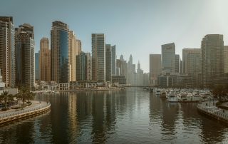 City skyline reflected in calm Dubai Marina waters at golden hour