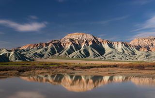 Colorful hills and reflective lake in desert landscape at sunrise