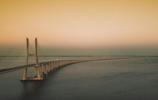 Modern bridge enveloped in golden fog at sunrise – architectural marvel in serene coastal setting