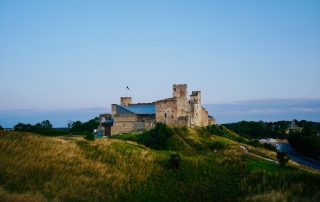 Historic stone castle on grassy hill beside Baltic Sea in Estonia