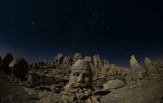 Stone-carved heads under a starry night sky in Cappadocia