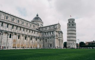Historic European palace with green lawn and leaning tower of pisa