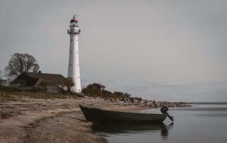Lighthouse standing on rocky shoreline in Estonia during overcast weather