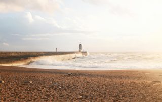 Solitary lighthouse on expansive beach in Portugal – tranquil coastal scenery